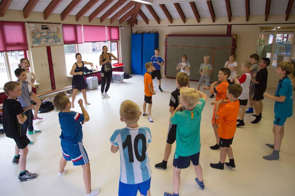 Kinderen doen samen een sportieve activiteit in een gymzaal