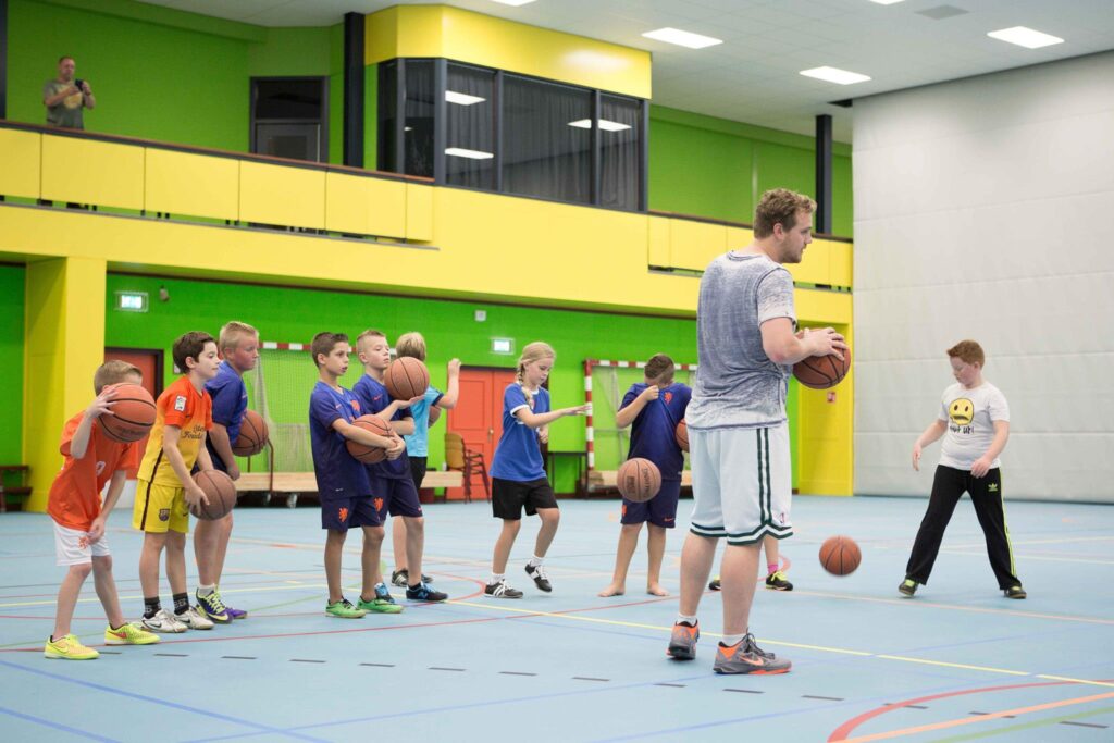 Kinderen oefenen basketbal tijdens een training in de sporthal