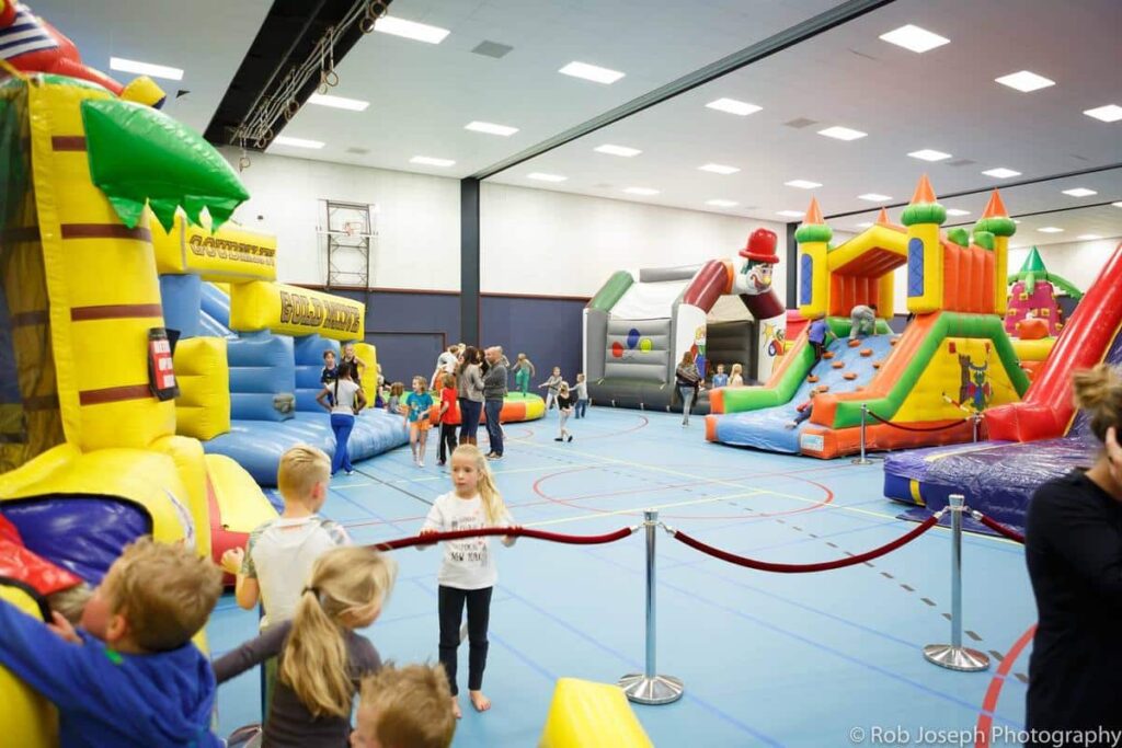 Kinderen spelen op groot en kleurrijke springkussens in een sporthal