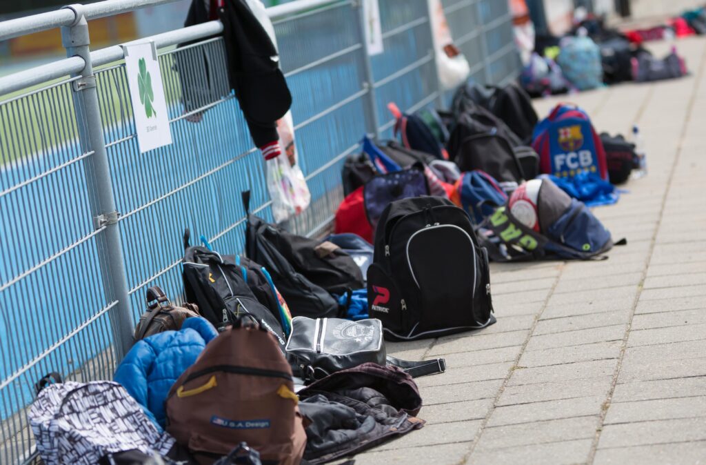 Rugzakken en sporttassen van kinderen langs een sportveld